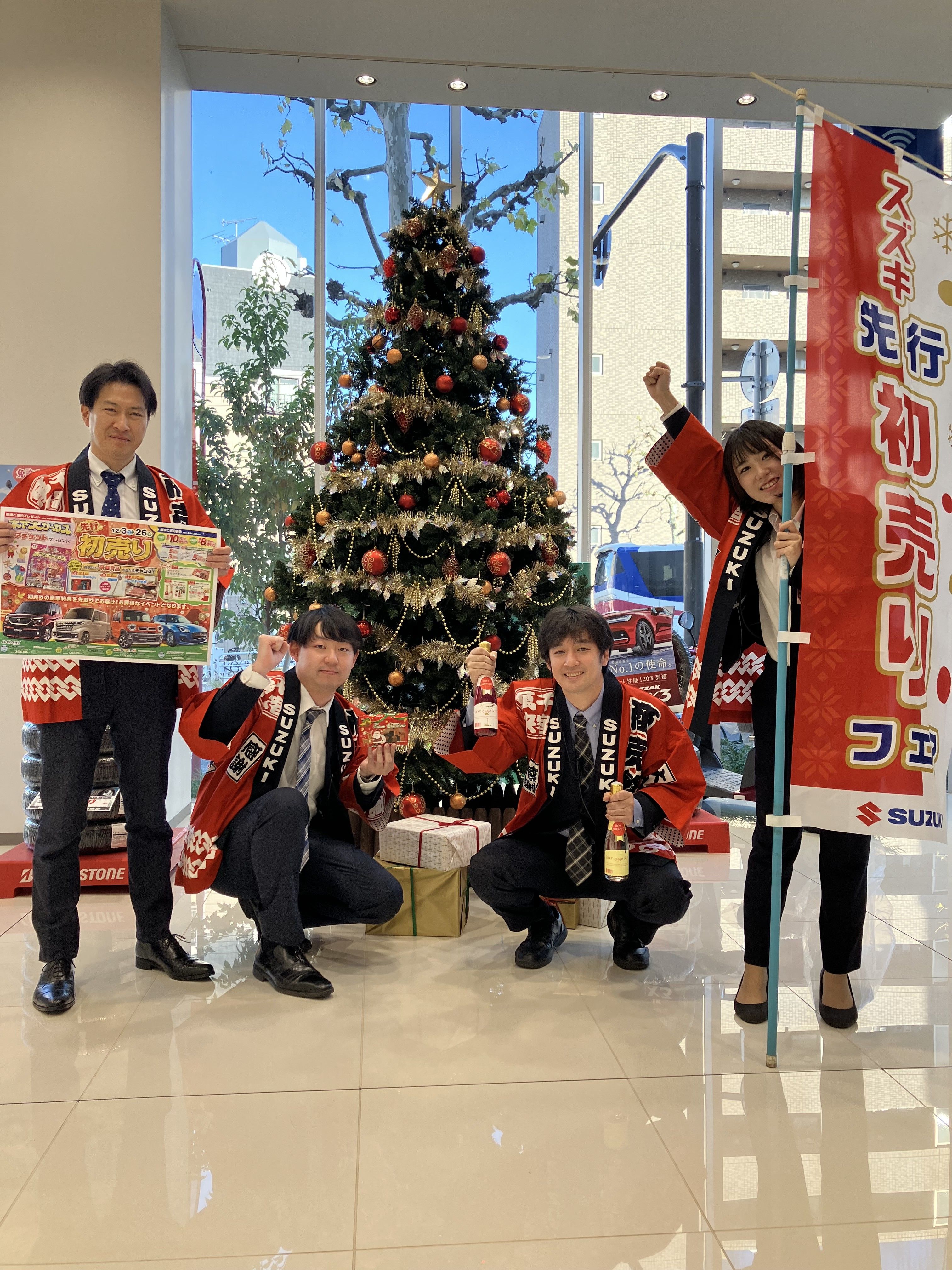 クリスマスツリーの前で頑張っているスタッフ